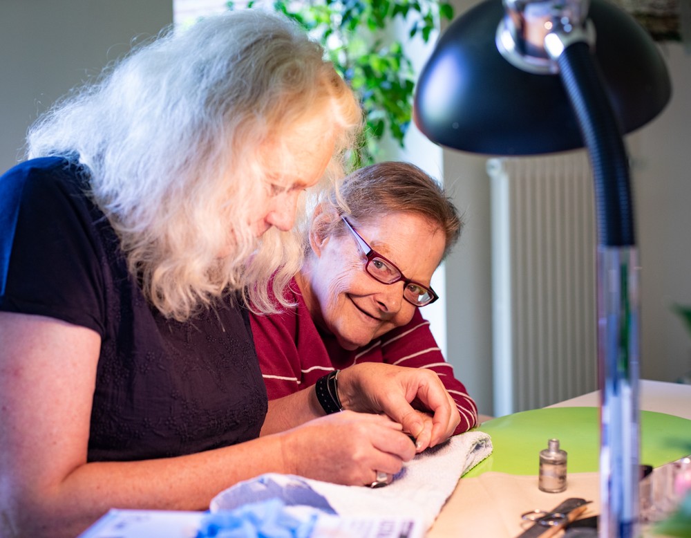 Eine Pflegekraft lackiert einer Bewohnerin die Fingernägel. Eine Pflegekraft lackiert einer Bewohnerin die Fingernägel.