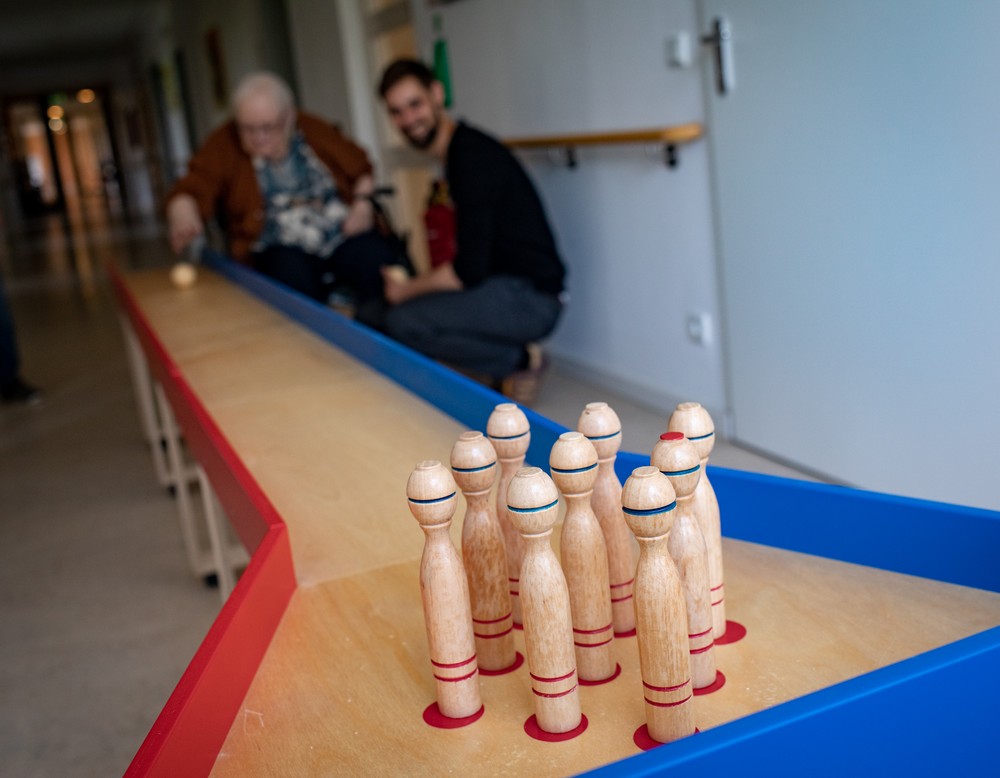 Herr Jungmann (Pflegedienstleitung) mit einer Bewohnerin an einer mobilen Kegelbahn. Herr Jungmann (Pflegedienstleitung) mit einer Bewohnerin an einer mobilen Kegelbahn.