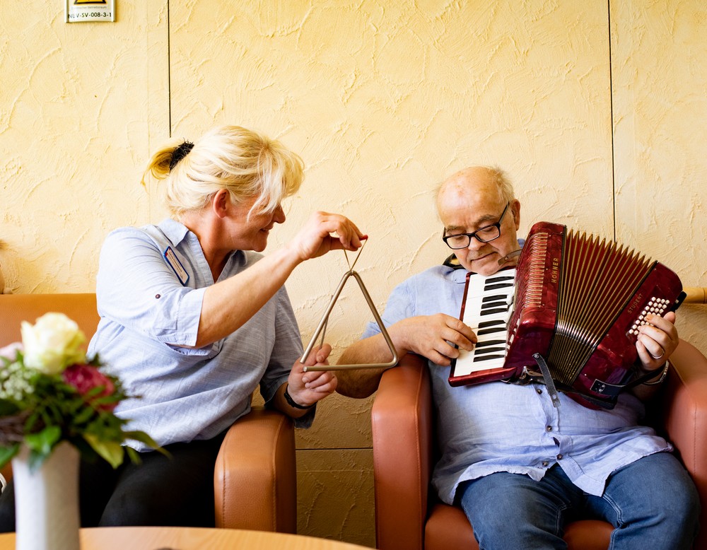Eine Therapeutin beim Musizieren mit einem Bewohner, der Akkordeon spielt. Eine Therapeutin beim Musizieren mit einem Bewohner, der Akkordeon spielt.